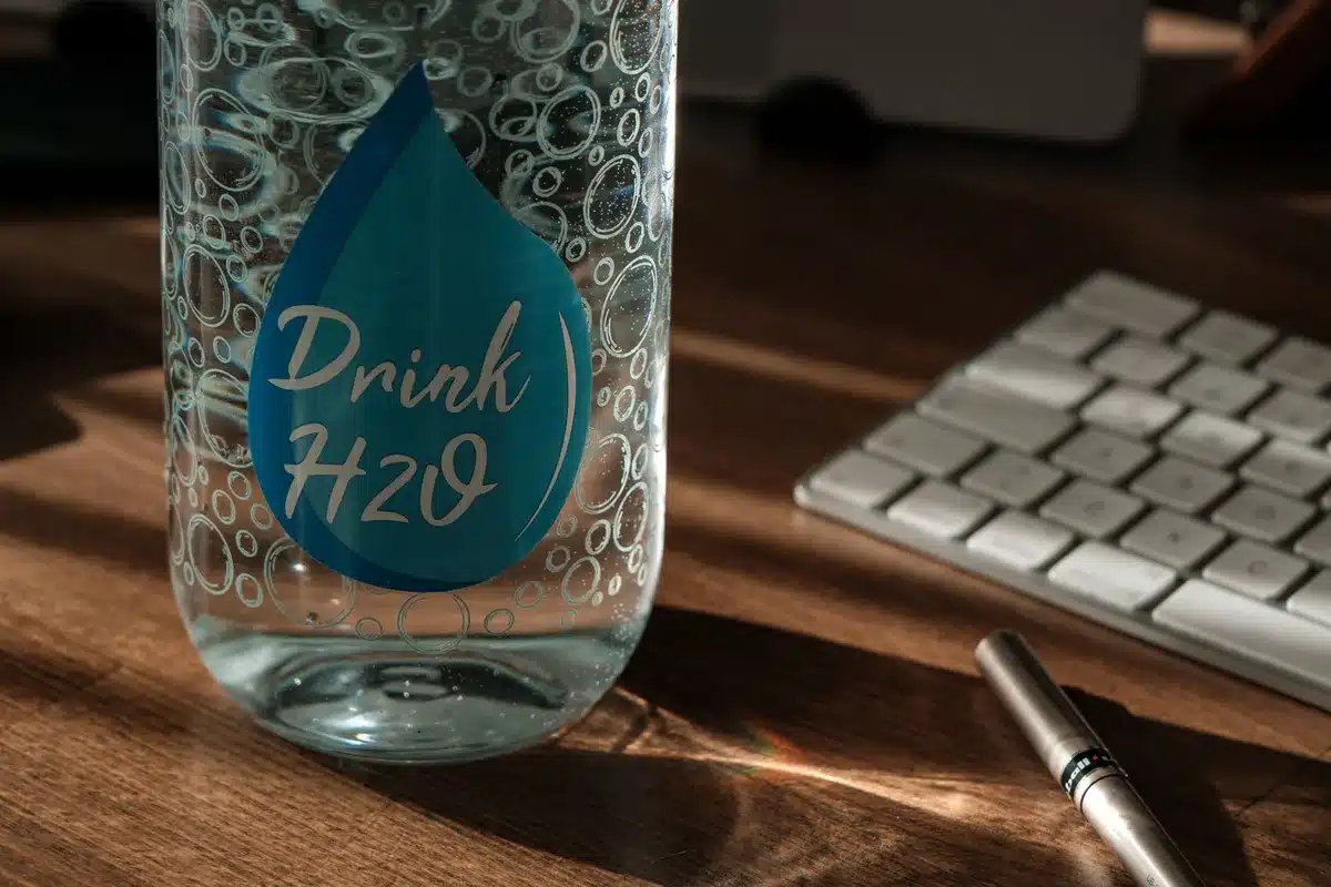A visible water bottle on a desk as part of a daily hydration routine