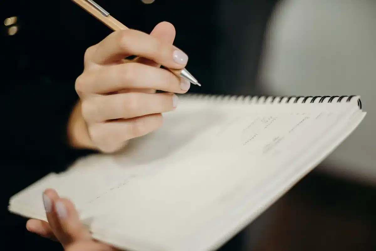 Person writing in health diary to track pain and sleep patterns
