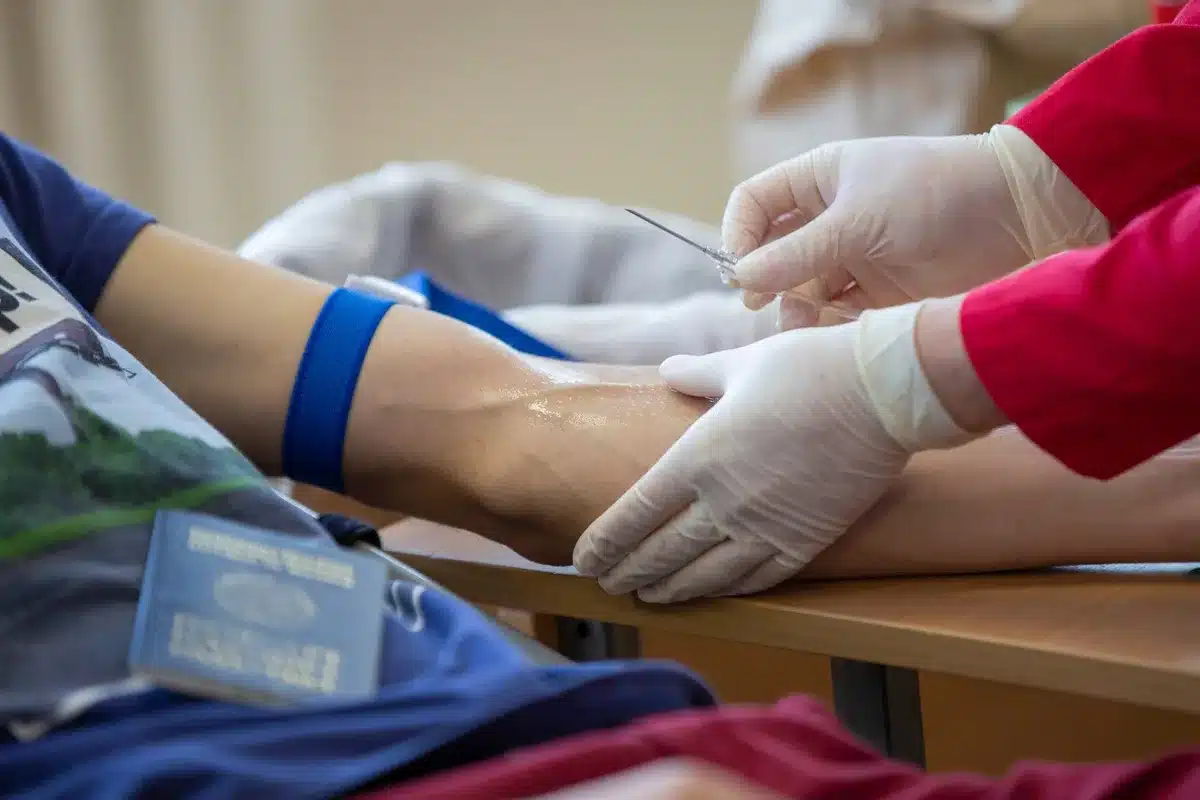 Healthcare provider drawing blood from a patient's arm in a clinical setting
