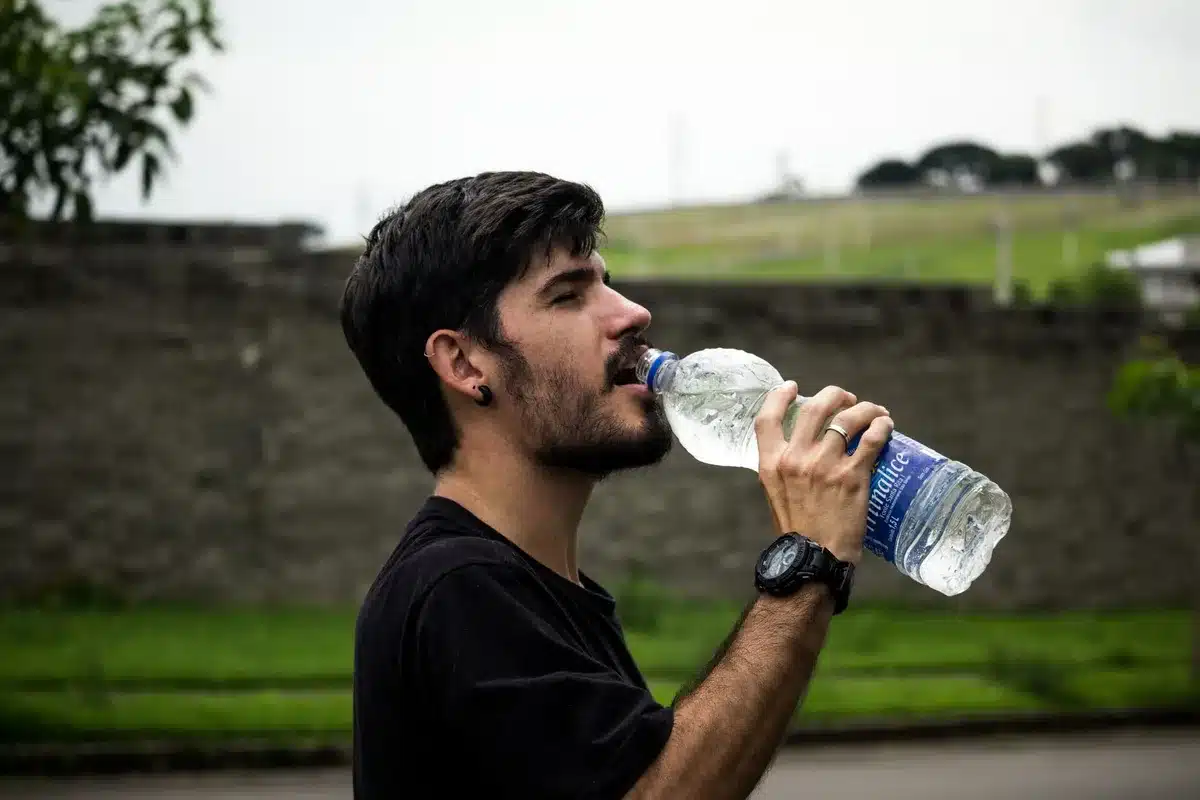 Person holding a glass of water, staying hydrated as part of daily wellness routine