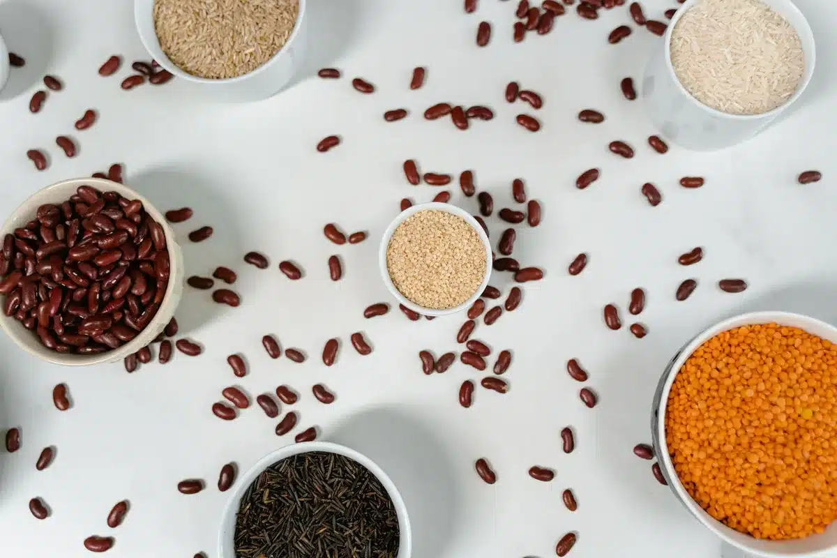 Variety of whole grains, legumes, and colorful vegetables arranged on a wooden surface