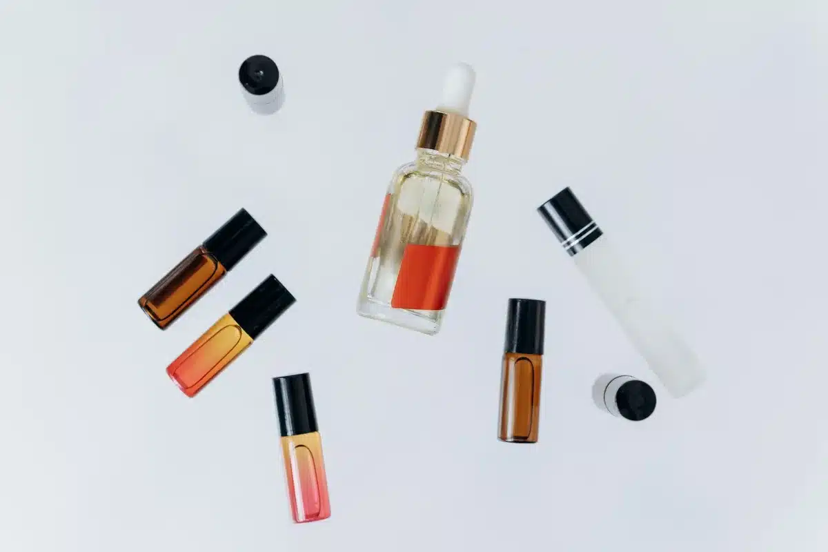 Hands diluting essential oil drops into a carrier oil in a small glass bowl