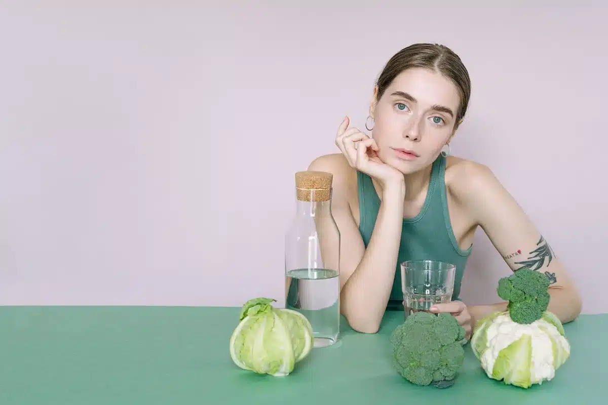 Glass of water and fresh vegetables on a table representing healthy dietary choices