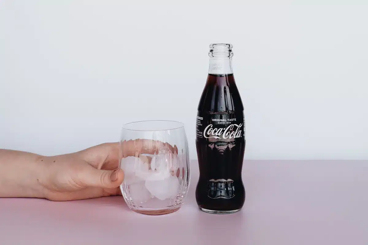A glass of cola or sugary soft drink on a table next to food