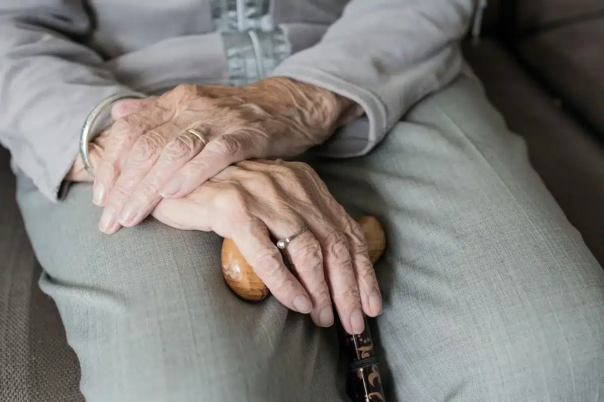 Older person using stairs with a hand on the railing in bright daylight