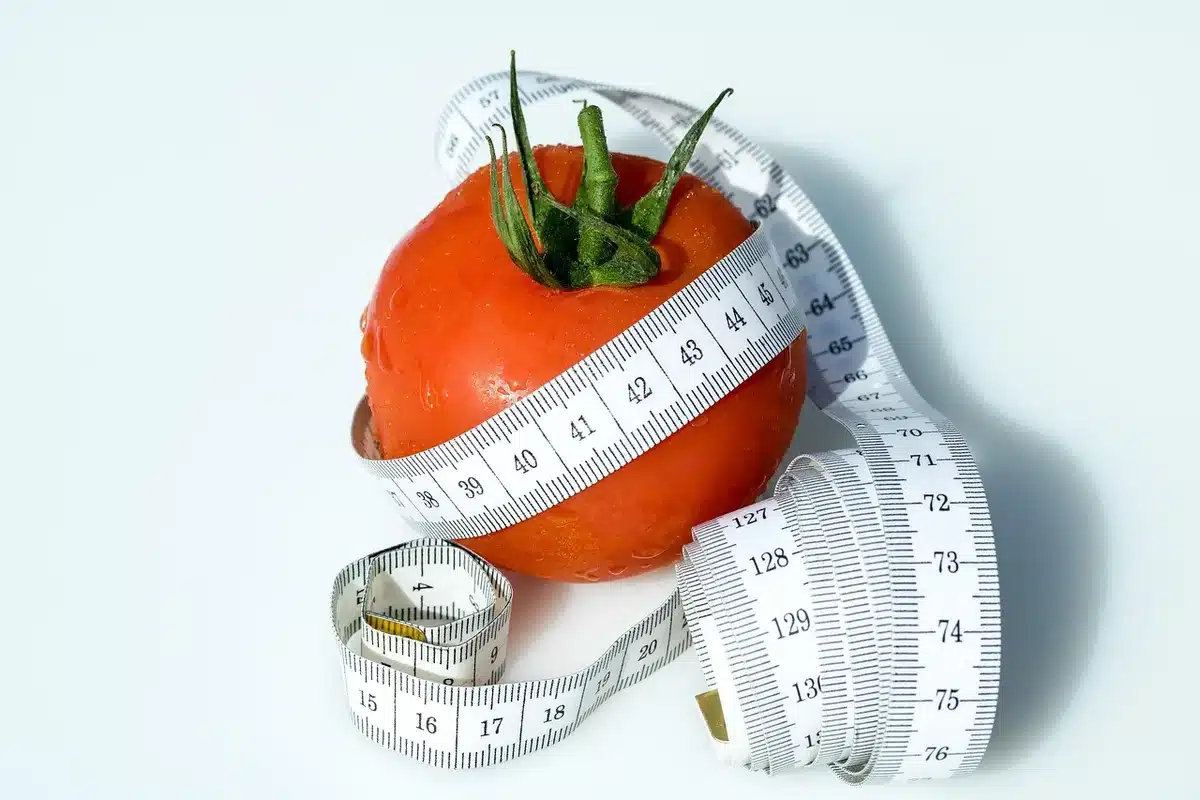 Hands measuring waist circumference at the navel with a tape measure