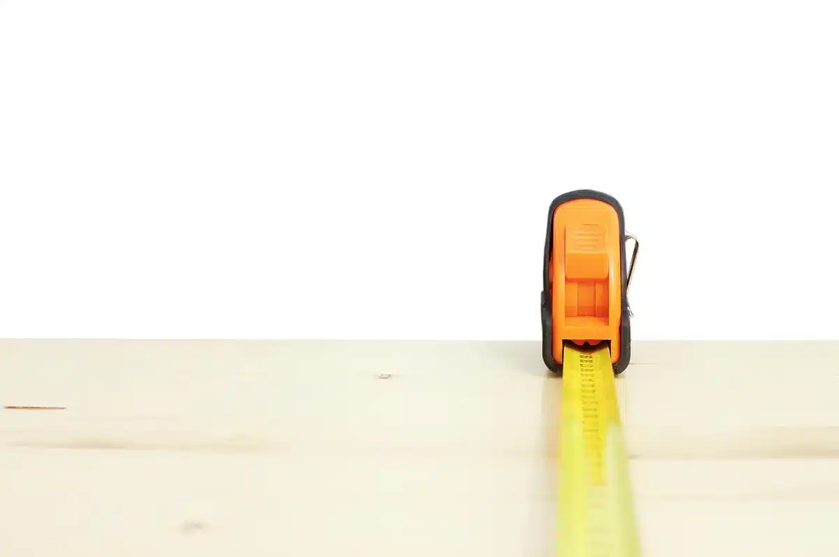 Person measuring waist with tape measure in a bright sunlit room (anonymous hands only)