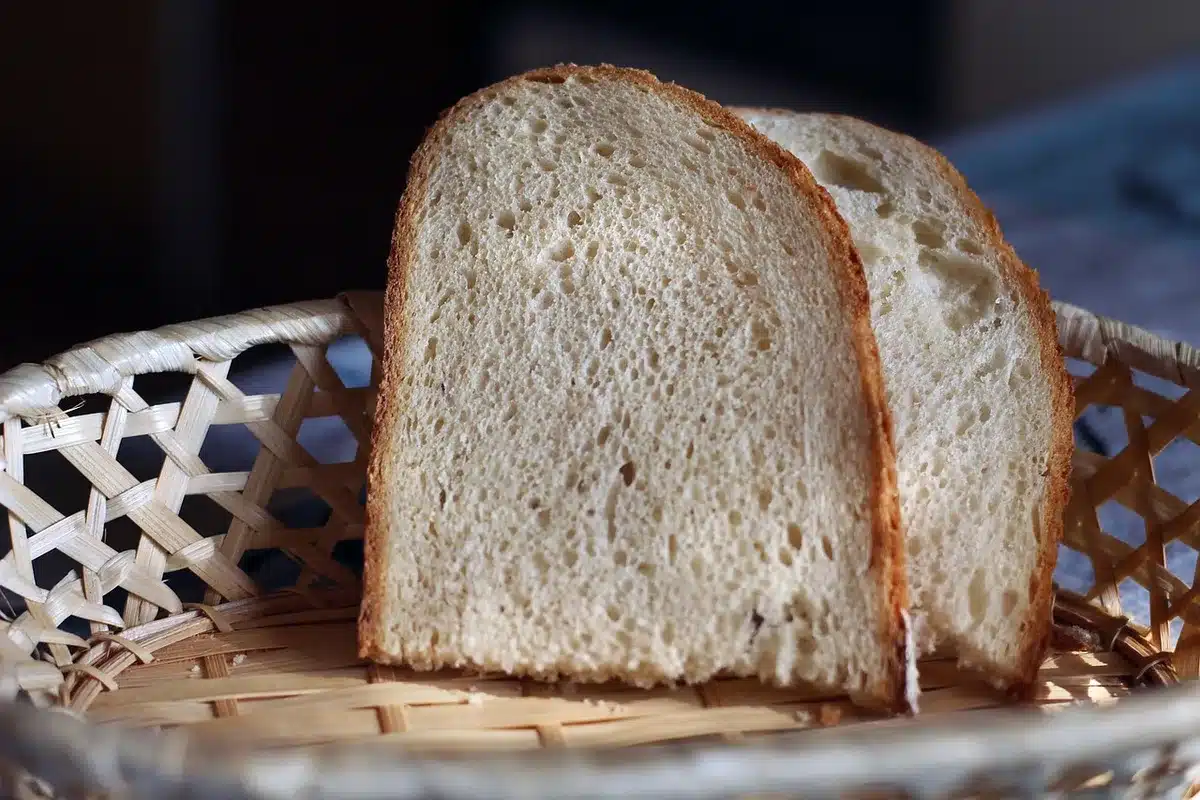Hands placing a slice of bread on a kitchen scale showing weight