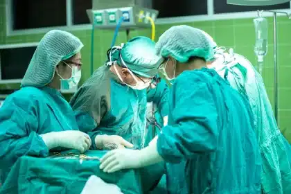 Patient knee in a bright clinic room with clinicians adjusting positioning for treatment