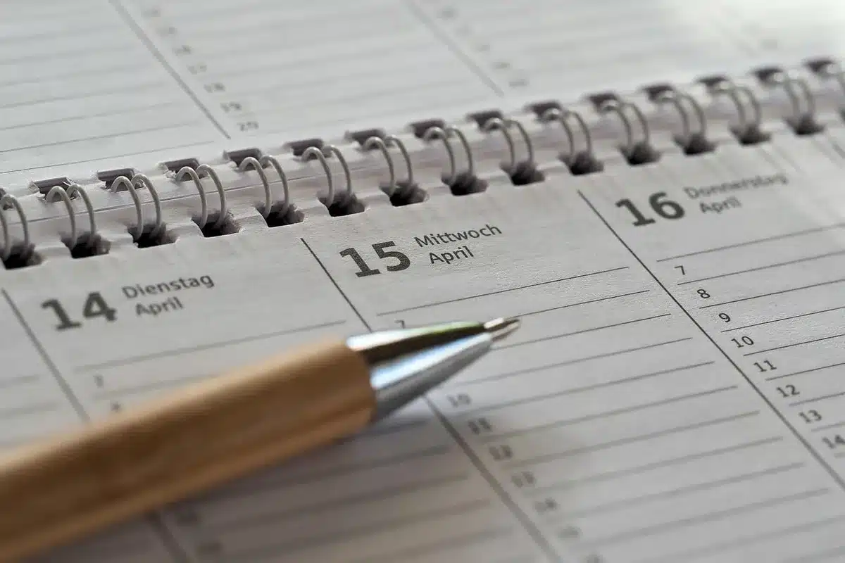 Calendar and pill organizer showing a stepwise medication reduction plan on a sunlit table